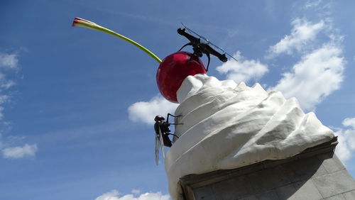 Low angle view of people on umbrella against sky