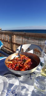 Food on table by sea against clear sky