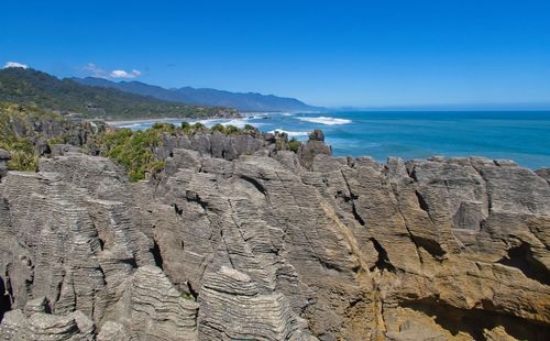 Scenic view of rocks in sea against blue sky