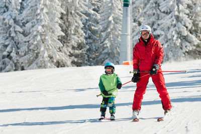 Full length of father and son skiing on snow during winter