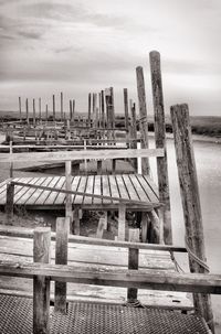 Wooden pier on beach against sky