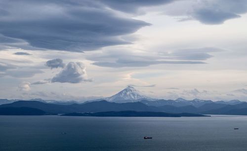 Scenic view of sea and snowcapped mountains against sky