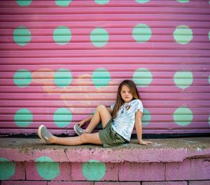 Full length portrait of teenage girl leaning against wall