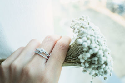 Close up an diamond ring on woman finger white holding white flowers. love and wedding concept. 