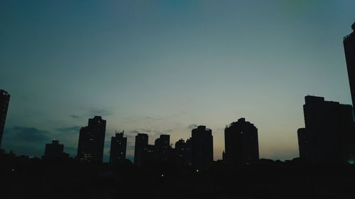 Silhouette buildings against sky at dusk