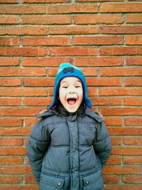 Portrait of a young man standing on brick wall