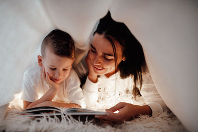 Mother and woman reading book on bed