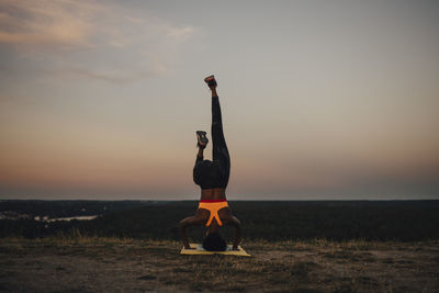 Young female athlete practicing yoga during sunset