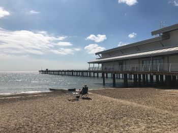 People sitting on beach by sea against sky