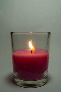 Close-up of lit tea light candle against gray background