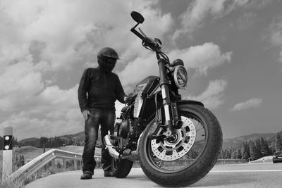 Rear view of man standing by motorcycle against sky