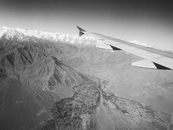 Airplane flying over mountains against sky