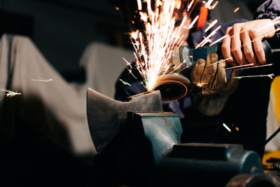 Worker sharpening axe with electric grinder