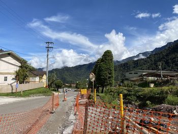 Road by buildings in city against sky