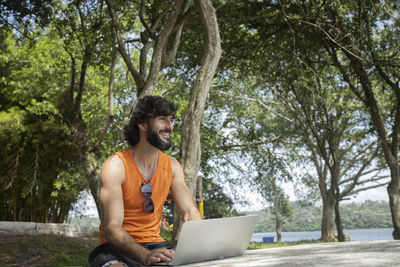 Man at a park on a beautiful sunny day with laptop. notebook work and leisure. green and nature
