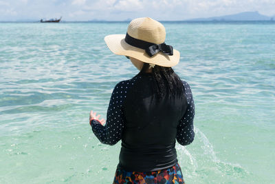 Rear view of woman standing by sea