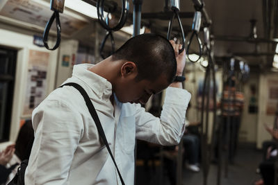 Side view of man using smart phone standing in train