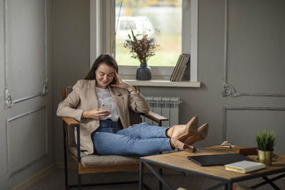 Full length photo of delighted positive lady sit chair put legs table accomplish. work-life-balance