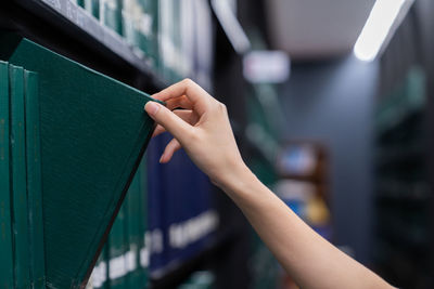 Close-up of hand removing book from shelf in library