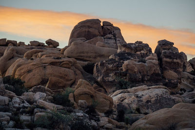 Rocks on shore against sky during sunset