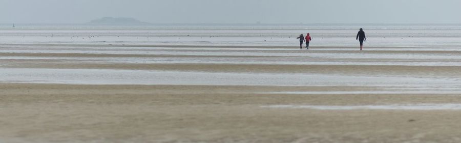 People walking on beach against sky