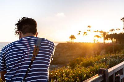 Rear view of man standing against sky during sunset