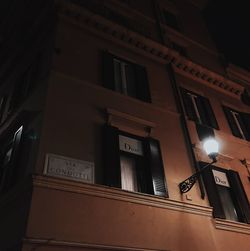 Low angle view of illuminated street light against building at night
