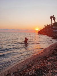 Silhouette people on beach against sky during sunset