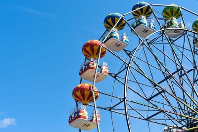 Low angle view of ferris wheel against clear blue sky