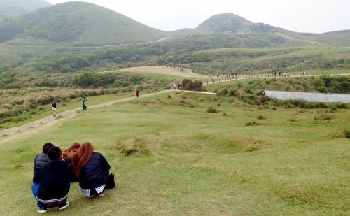 People hiking on grassy field