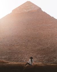 Rear view of woman sitting on mountain