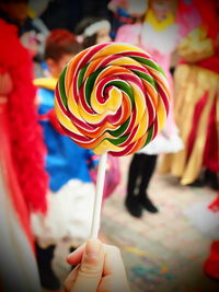 Cropped hand holding colorful lollipop during parade