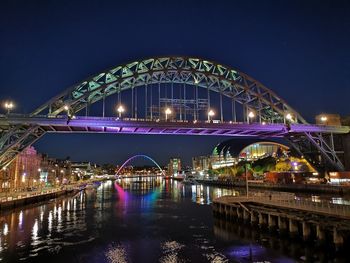 Illuminated bridge over river at night