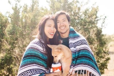 Portrait of a smiling couple with dog covered in blanket