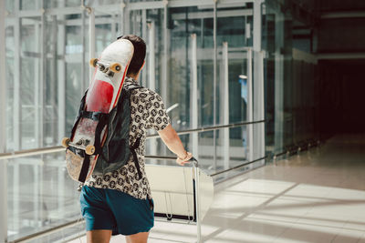 Young man walking at the airport with skateboard on his back