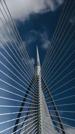 Low angle view of suspension bridge against cloudy sky