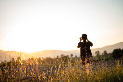 Woman standing on land against sky during sunset