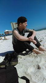 Young man using mobile phone while sitting on beach