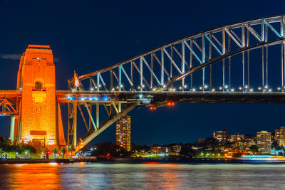 Illuminated bridge over river against sky at night