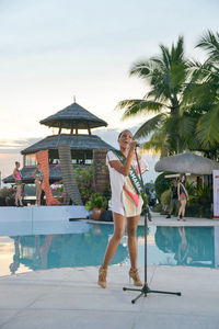 Woman standing by swimming pool against sky