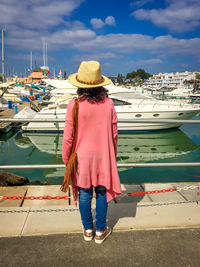 Rear view of woman standing on boat moored at harbor