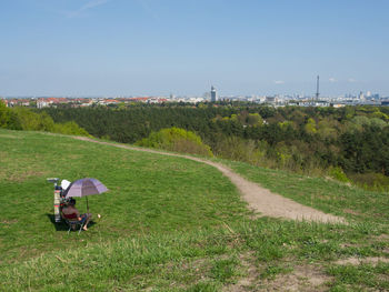 Old man sitting under umbrella with view over city on teufelsberg mountain, berlin, germany