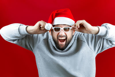 Portrait of young man wearing hat against red background