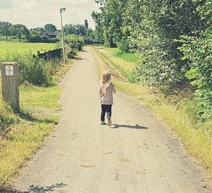 Rear view of woman walking on footpath