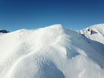 Scenic view of snowcapped mountains against clear blue sky