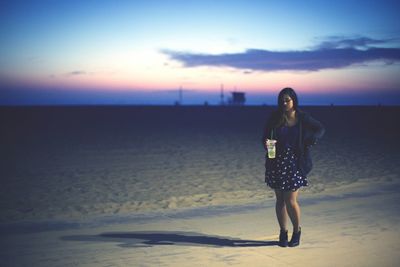 Woman standing on beach at sunset