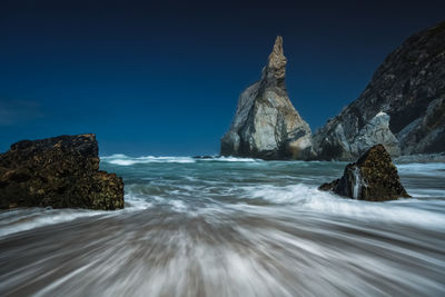 Rock formations in sea against clear sky