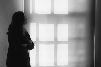 Thoughtful woman with arms crossed looking at wall