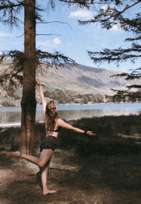 Full length of woman with arms raised in lake