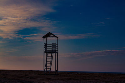 Lifeguard hut on beach against sky during sunset